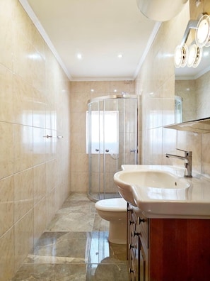 A modern bathroom with a glass-enclosed shower, a vanity with a sink, and a mirror with lights. - The Boat House apartment (Wied il-Għajn)