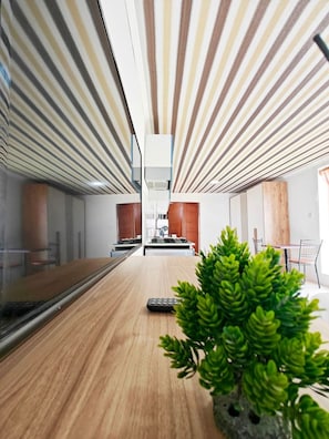 A modern kitchen with a wooden countertop, a central island, and a potted plant.