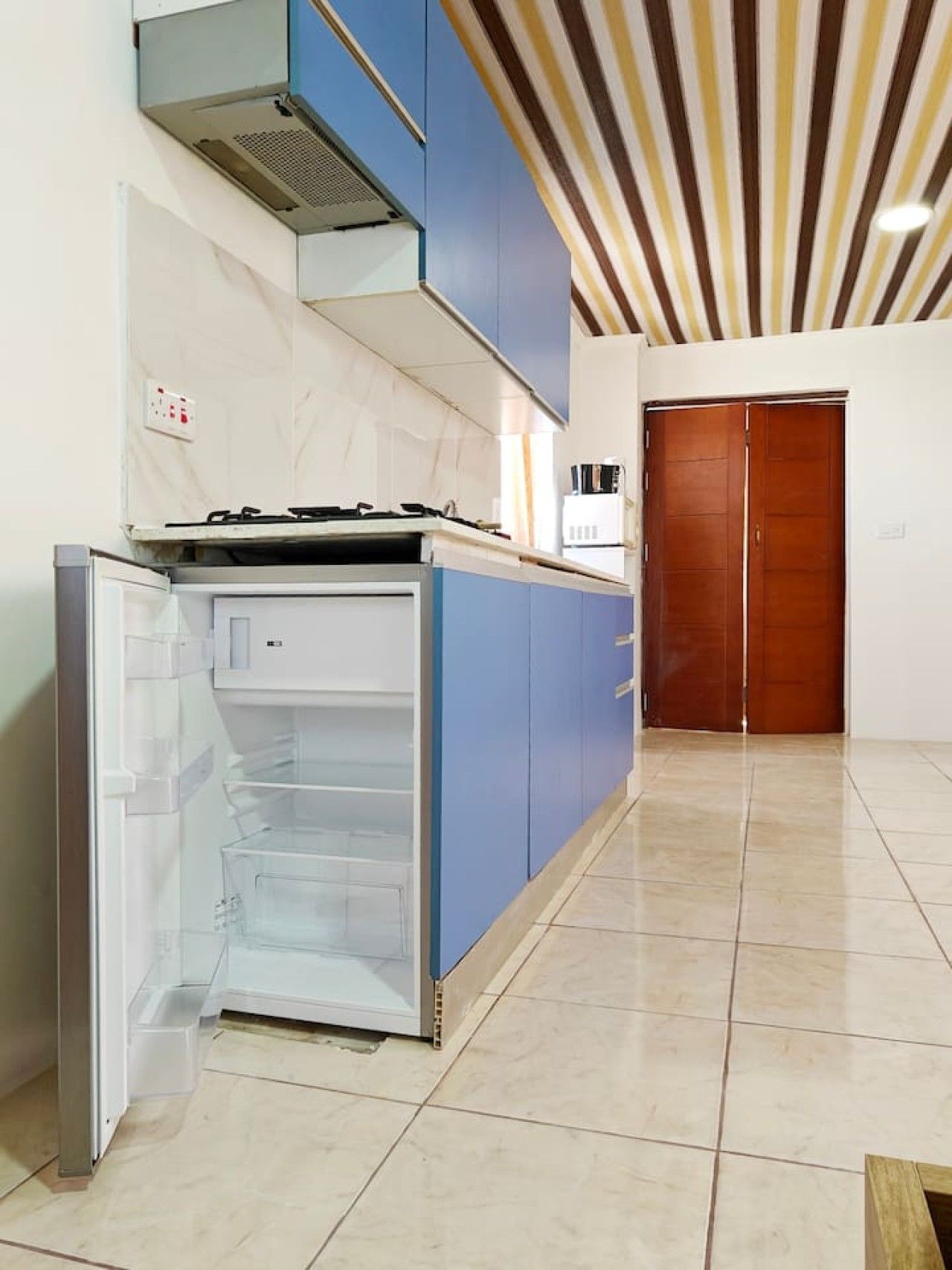 A kitchen with a built-in refrigerator, a stove, and blue cabinets.