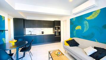 A modern living space with a dining area, a sofa, and a kitchen in the background.