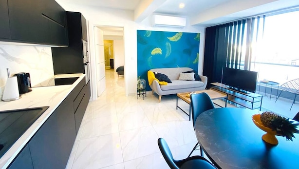 Una cocina moderna con armarios oscuros y una zona de comedor con una mesa y sillas azules.