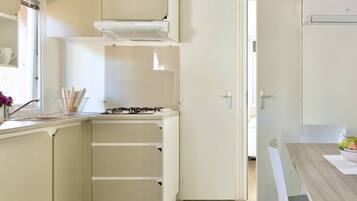 A compact kitchen with a gas stove, a built-in oven, and a white cabinet.