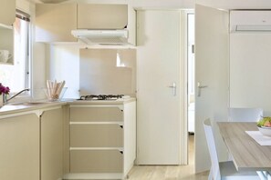 A compact kitchen with a gas stove, a built-in oven, and a white cabinet.