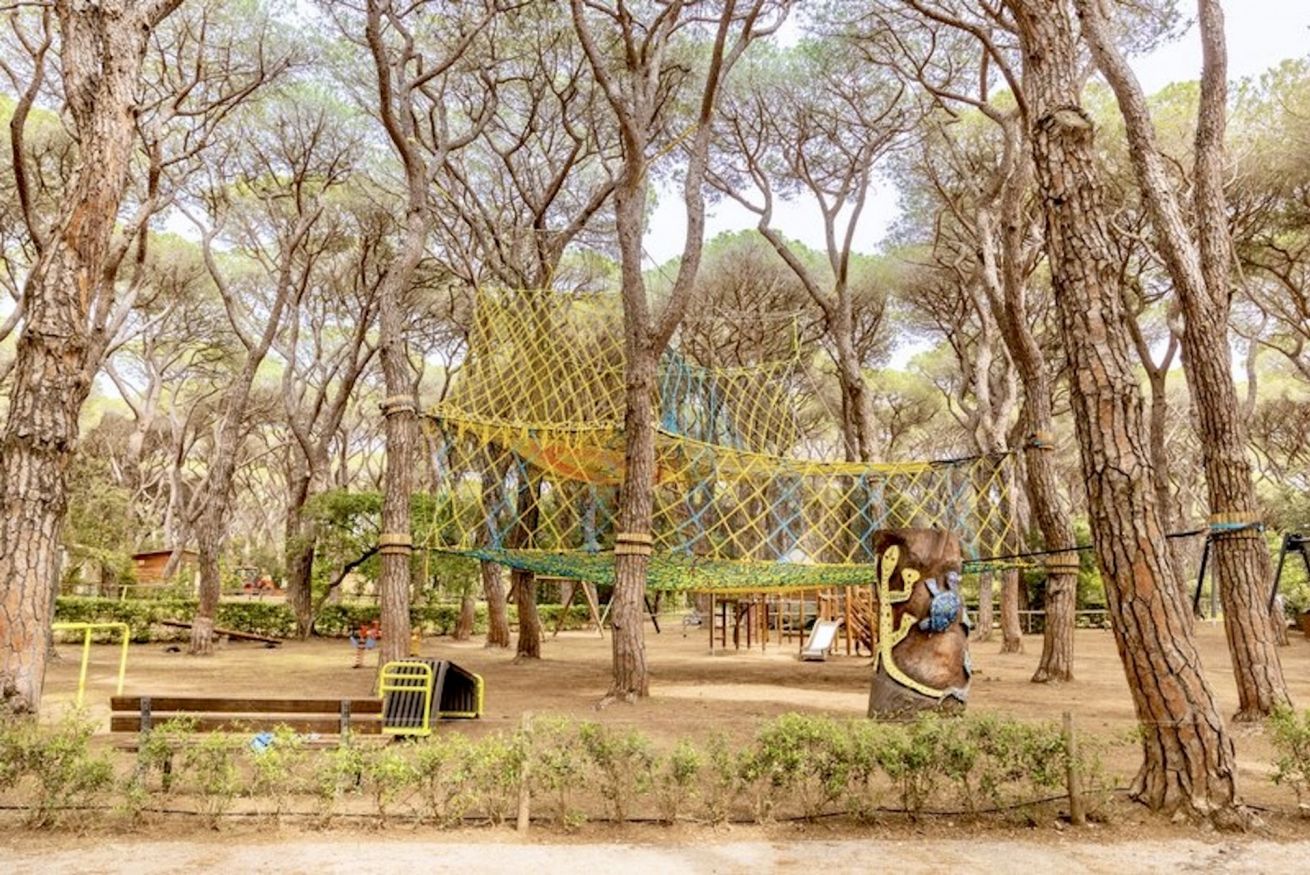 A playground with a rope bridge, swings, and a net structure.
