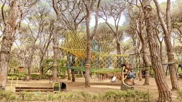A playground with a rope bridge, swings, and a net structure.