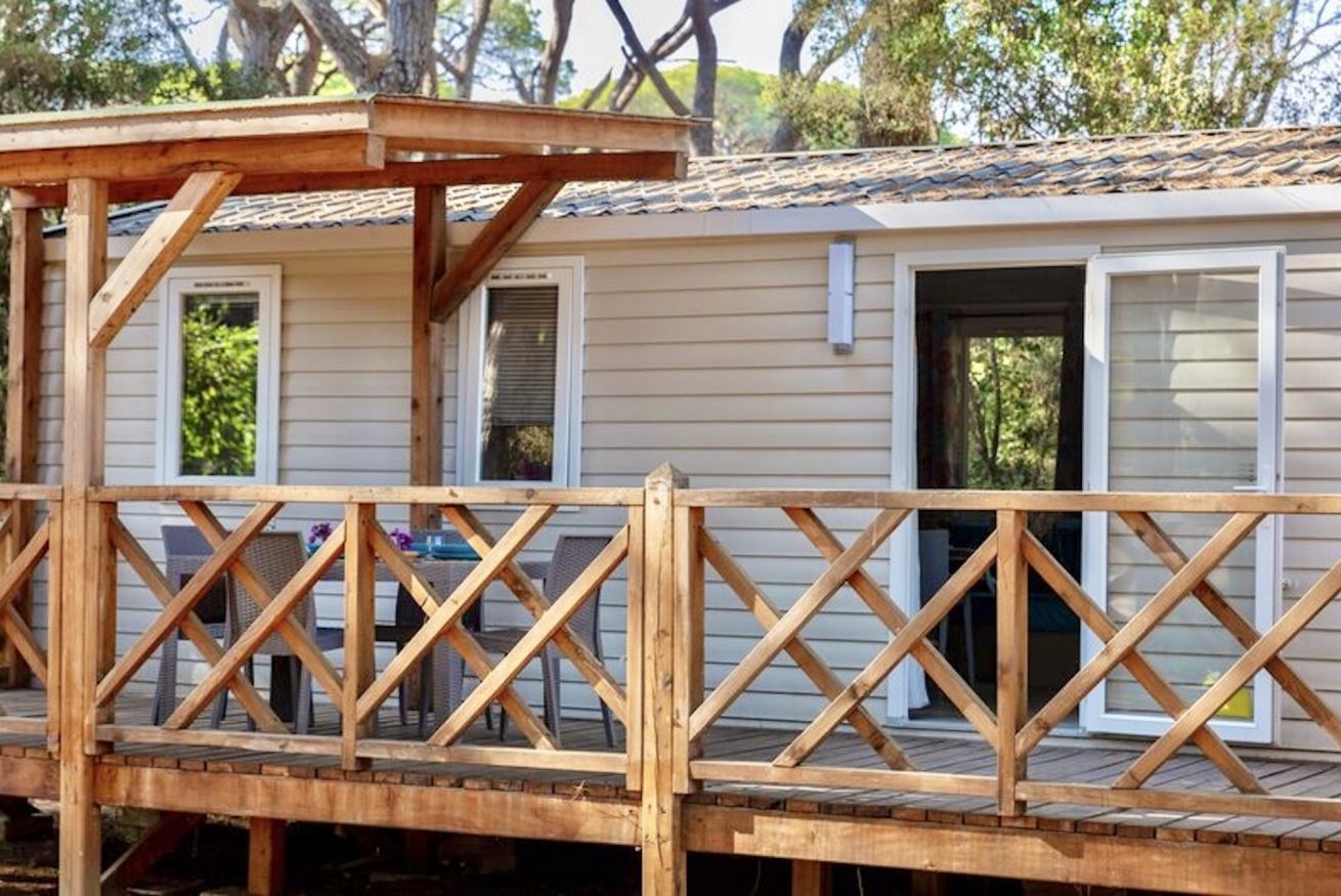 A wooden deck with a railing, a covered area, and a building with windows and doors.