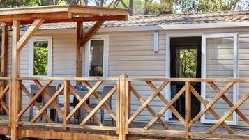 A wooden deck with a railing, a covered area, and a building with windows and doors.