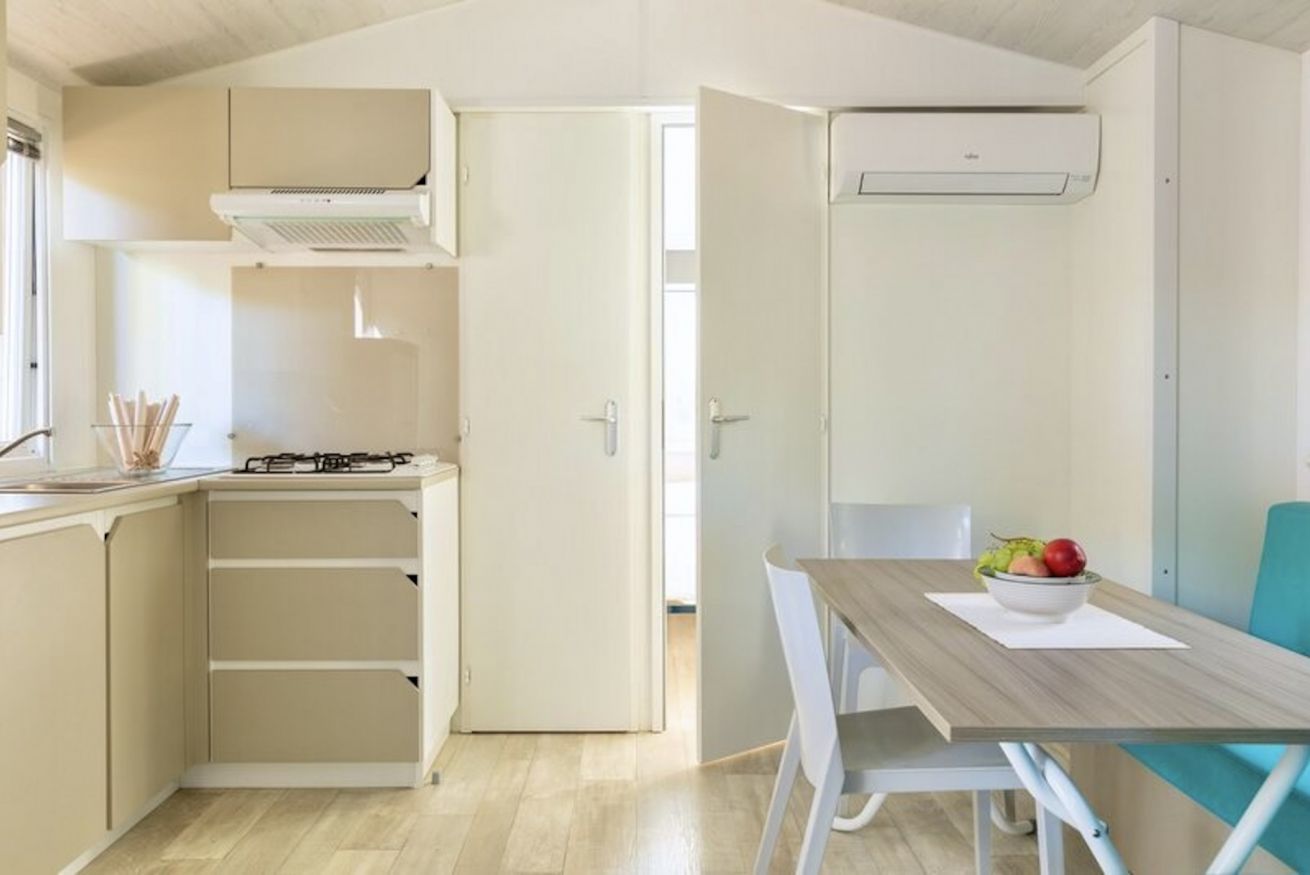 Una cucina compatta con piano cottura a gas, forno integrato e mobiletto bianco.
