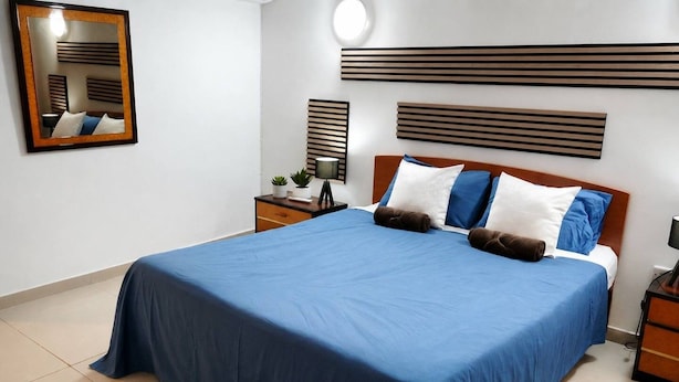 Una camera d'albergo con un letto grande, un comodino, uno specchio e un lampadario a parete.