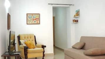 A living room with a sofa, armchair, and a television on a stand.