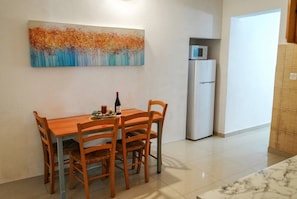 A dining area with a wooden table and chairs, a painting on the wall, a refrigerator, and a tiled floor. - Valletta Retreat apartment (Valletta)