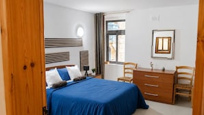 Una camera da letto con un letto, una scrivania, due sedie, una finestra e un quadro appeso al muro.