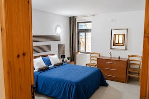 A bedroom with a bed, a desk, two chairs, a window, and a wall-mounted picture. - Valletta Retreat apartment (Valletta)