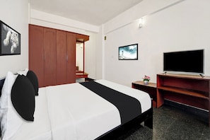 A hotel room with a bed, a television, a desk, and a wardrobe. - Hotel O East Fort (Thiruvananthapuram)