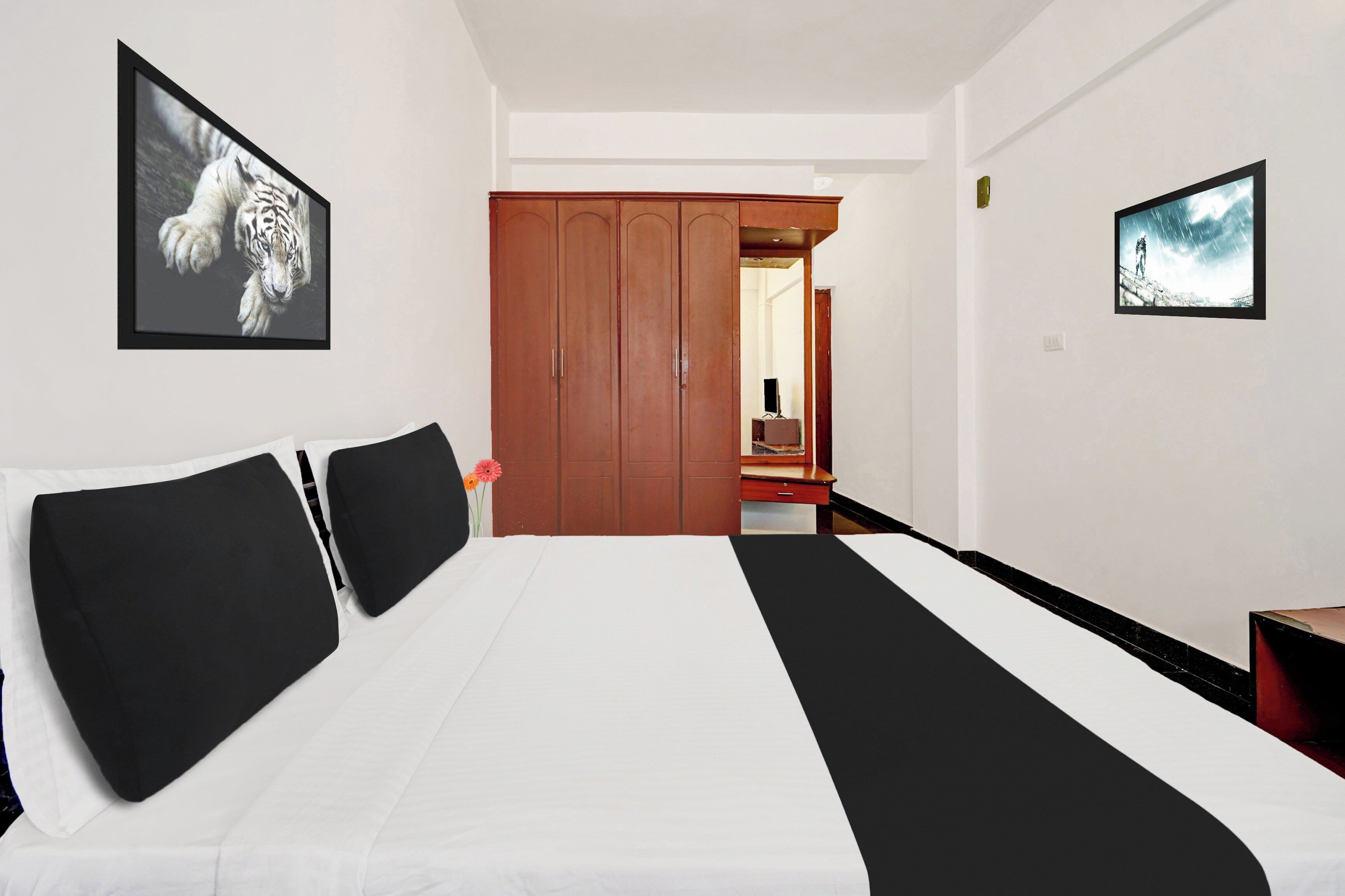 Ein Hotelzimmer mit einem Bett, einem Kleiderschrank und zwei gerahmten Bildern an der Wand.
