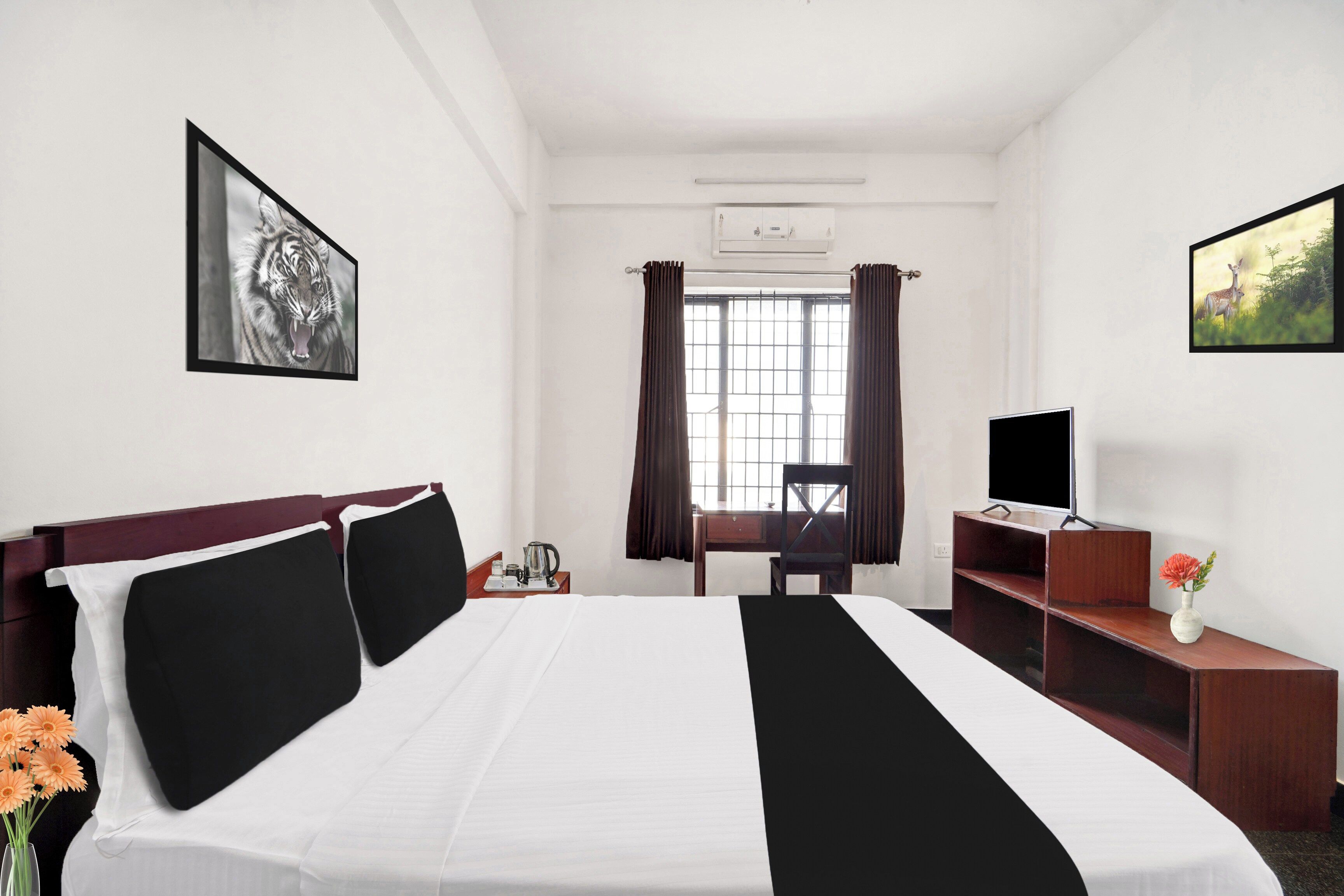 A hotel room with a bed, a desk, a chair, a television, and a window with curtains.