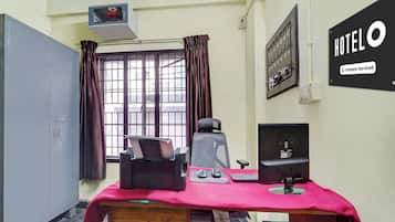 A hotel room with a desk, chair, computer, and a window with curtains.
