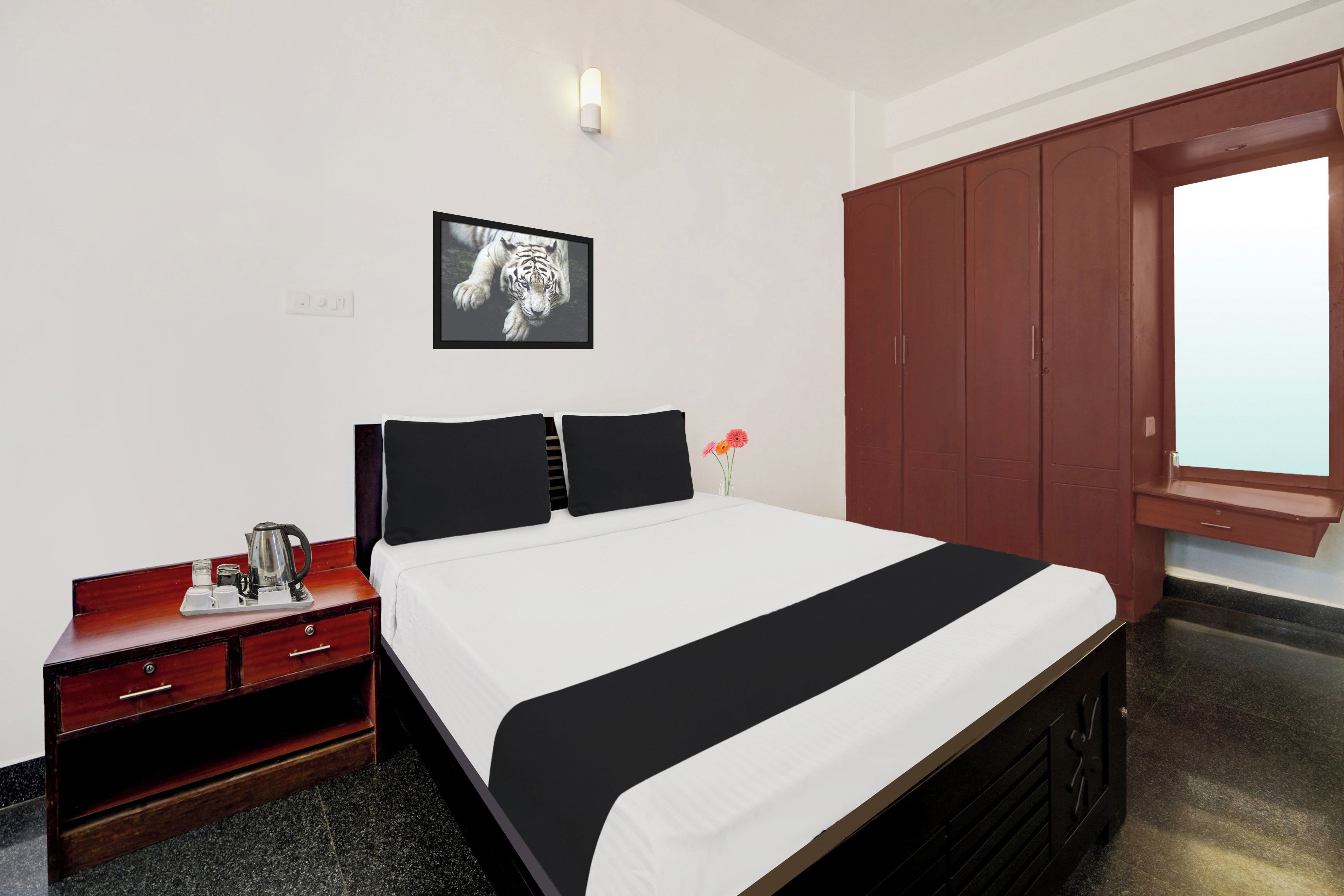 A hotel room with a bed, a nightstand, a wardrobe, and a framed picture on the wall.