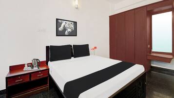 A hotel room with a bed, a nightstand, a wardrobe, and a framed picture on the wall.