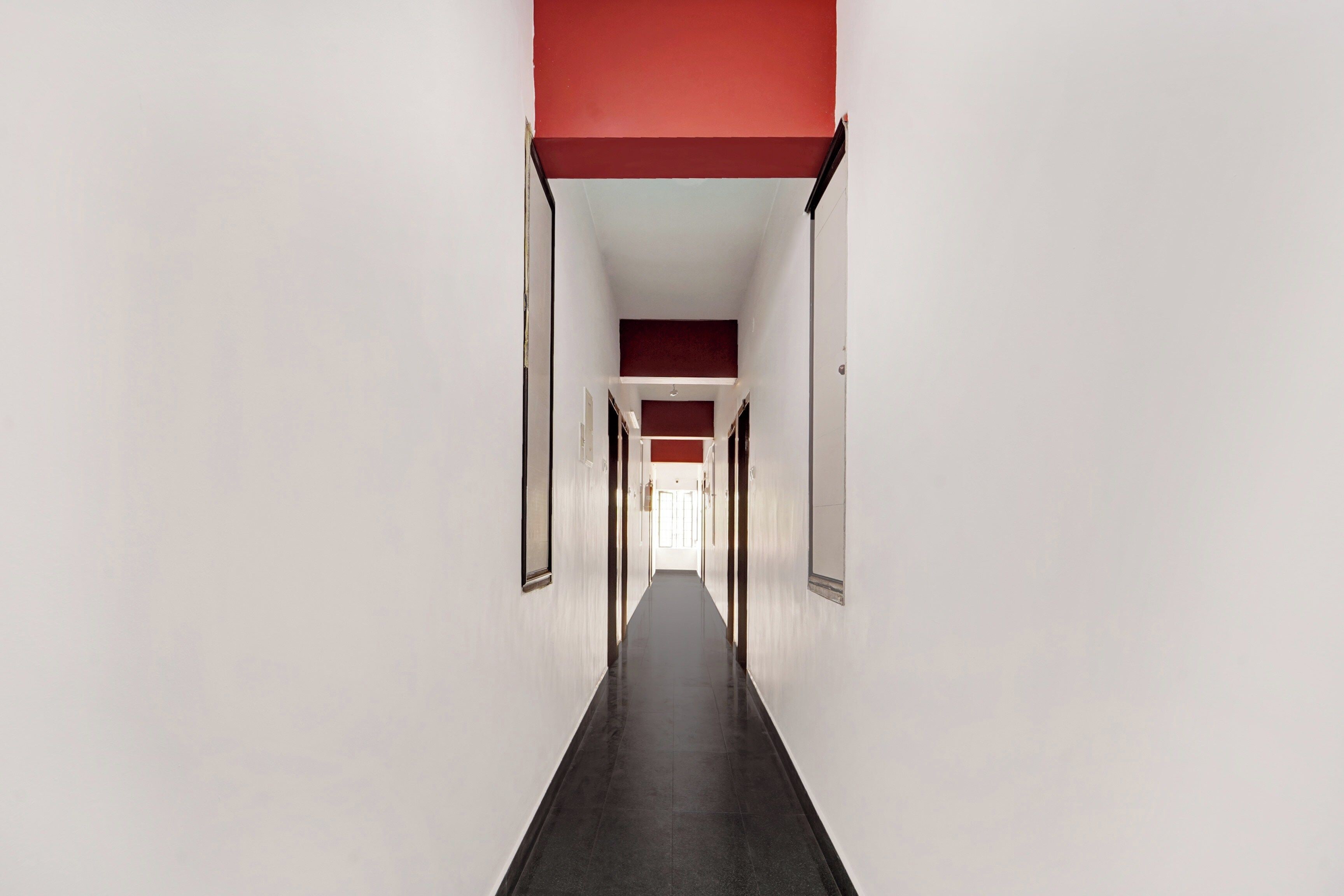 A long, narrow hallway with white walls and a red ceiling.