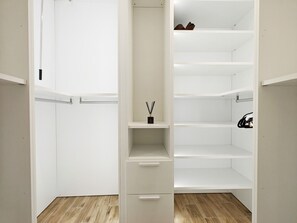 A walk-in closet with open shelves, a hanging rod, and a small drawer unit. - Black Diamond apartment (Żabbar)