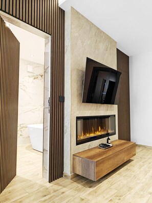 A modern interior with a fireplace, a TV mounted on a textured wall, and a wooden bench. - Black Diamond apartment (Żabbar)