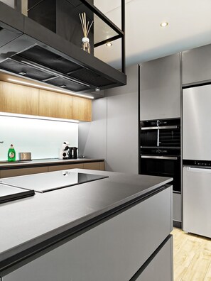 A modern kitchen with a central island, built-in oven, and stainless steel appliances. - Black Diamond apartment (Żabbar)