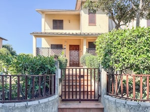 A two-story building with a gated entrance, a wooden door, and a balcony. - La Casa del Nespolo (Torrita di Siena)