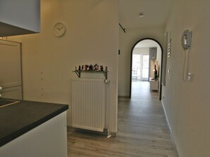 Ein Flur mit Heizkörper, einer Uhr und einer Tür zu einem anderen Zimmer.