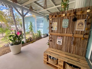 Et overdækket udendørs område med en trævæg pyntet med skilte, herunder et skilt med teksten 'Welcome to Our Beach House'.