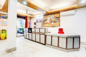 Zona de recepción con suelo de mármol, mostrador de recepción y un cuadro colgado en la pared.