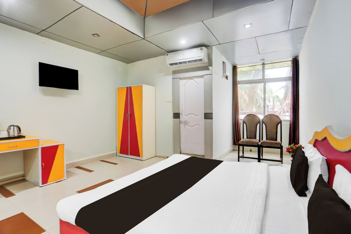 A hotel room with a bed, a desk, a wardrobe, a television, and a window with a view.