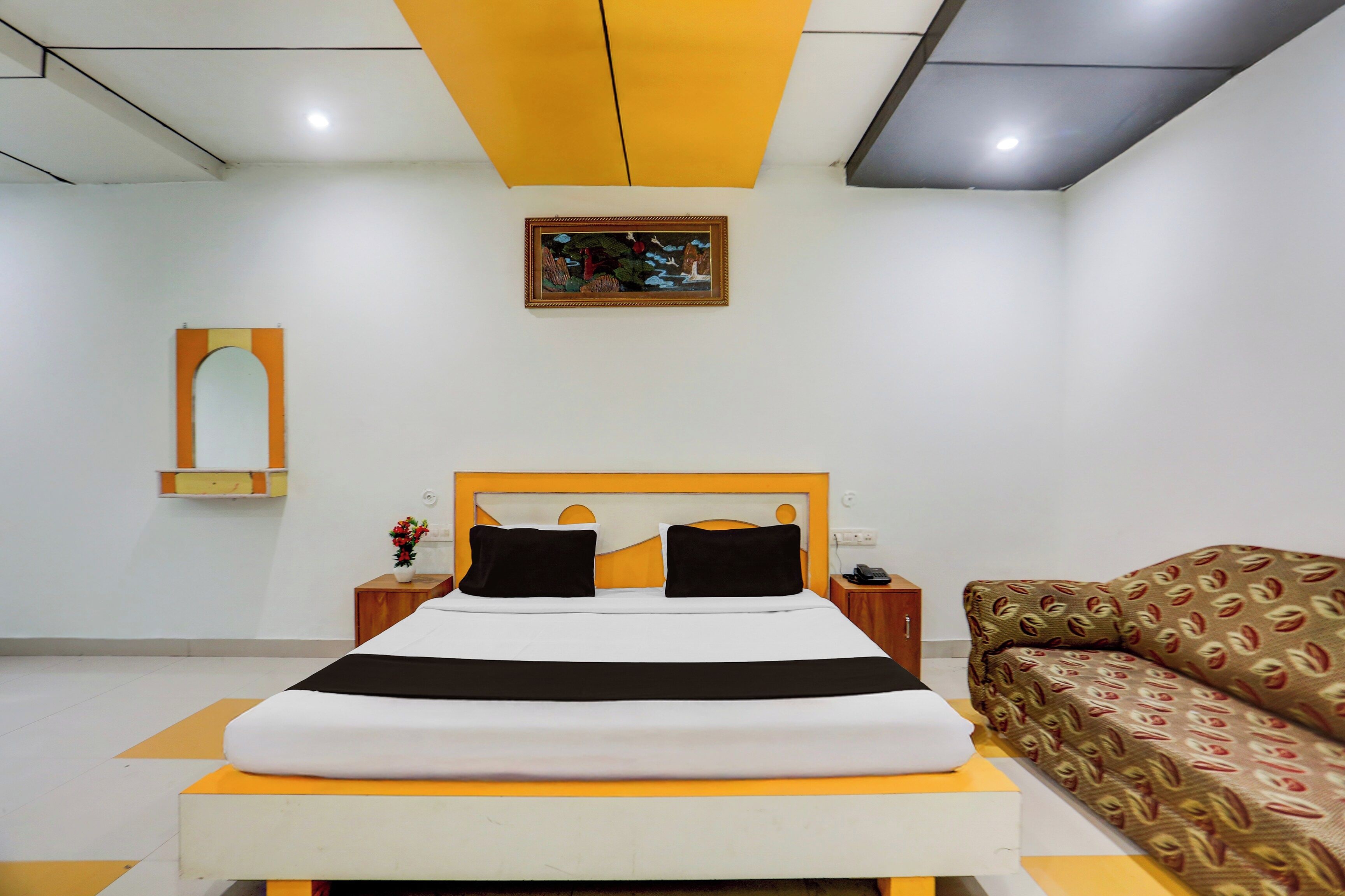 Una habitación de hotel con cama, sofá, un cuadro y espejo.