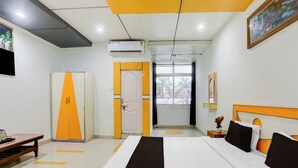 A hotel room with a bed, a wardrobe, a desk, and a window with a view. - Collection O Nandanpura Sipri Bazar (Jhansi)
