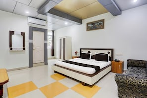 Una habitación de hotel con cama, mesita de noche y sofá.