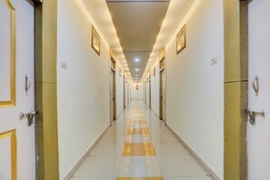 Pasillo de hotel con puertas a ambos lados, piso de baldosas e iluminación empotrada.