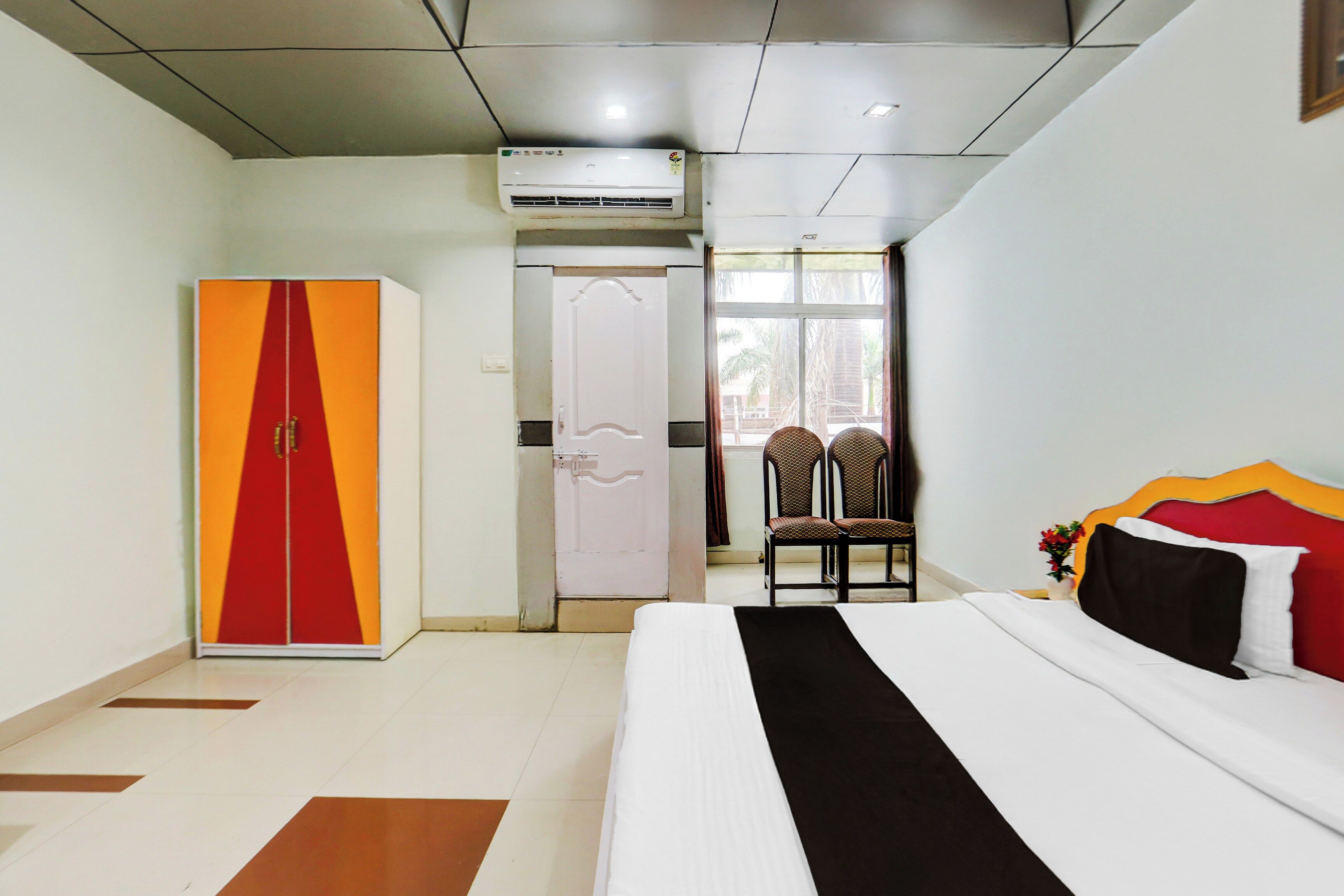A hotel room with a bed, a wardrobe, a chair, and a window with a view.