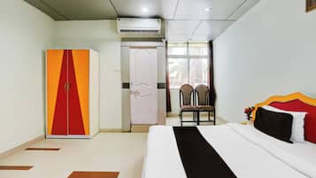 A hotel room with a bed, a wardrobe, a chair, and a window with a view.