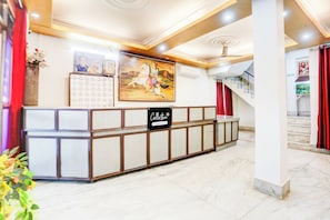 A reception area with a reception desk, a wall-mounted calendar, and a staircase with red curtains. - Collection O Nandanpura Sipri Bazar (Jhansi)