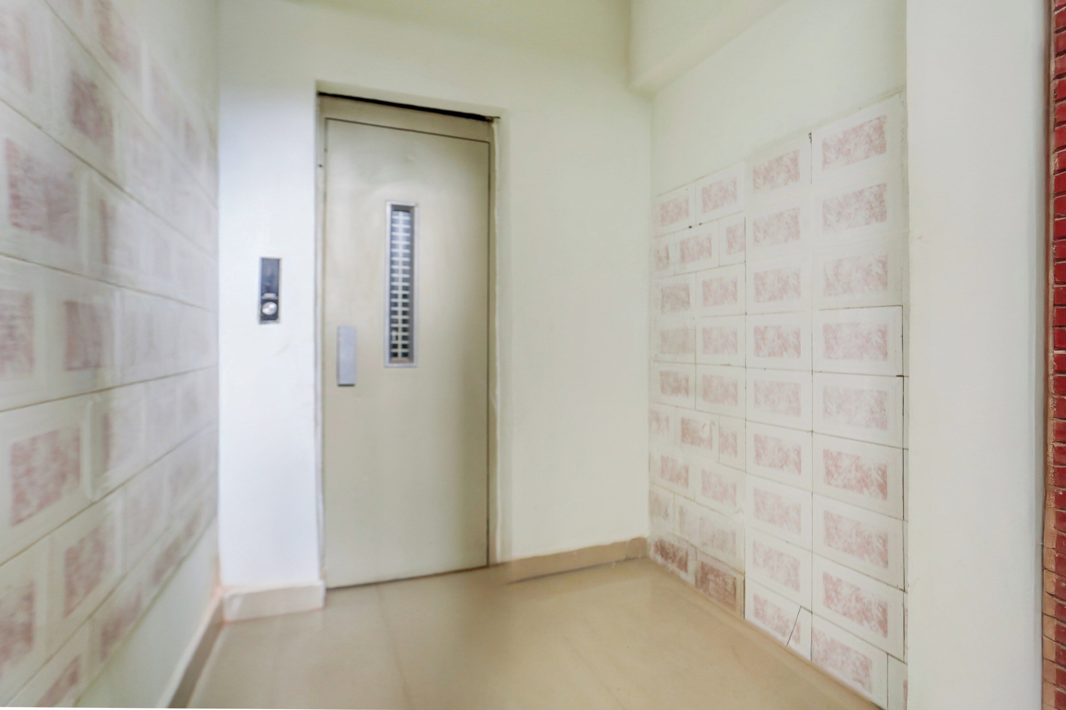 Ein Flur mit einer Tür, einem Wandaufzug und einer gefliesten Wand.