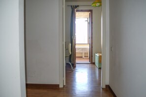 A hallway with a wooden floor leading to a room with a window and a curtain. - La Casa del Nespolo - Two-Story Townhouse in Torrita di Siena (Torrita di Siena)
