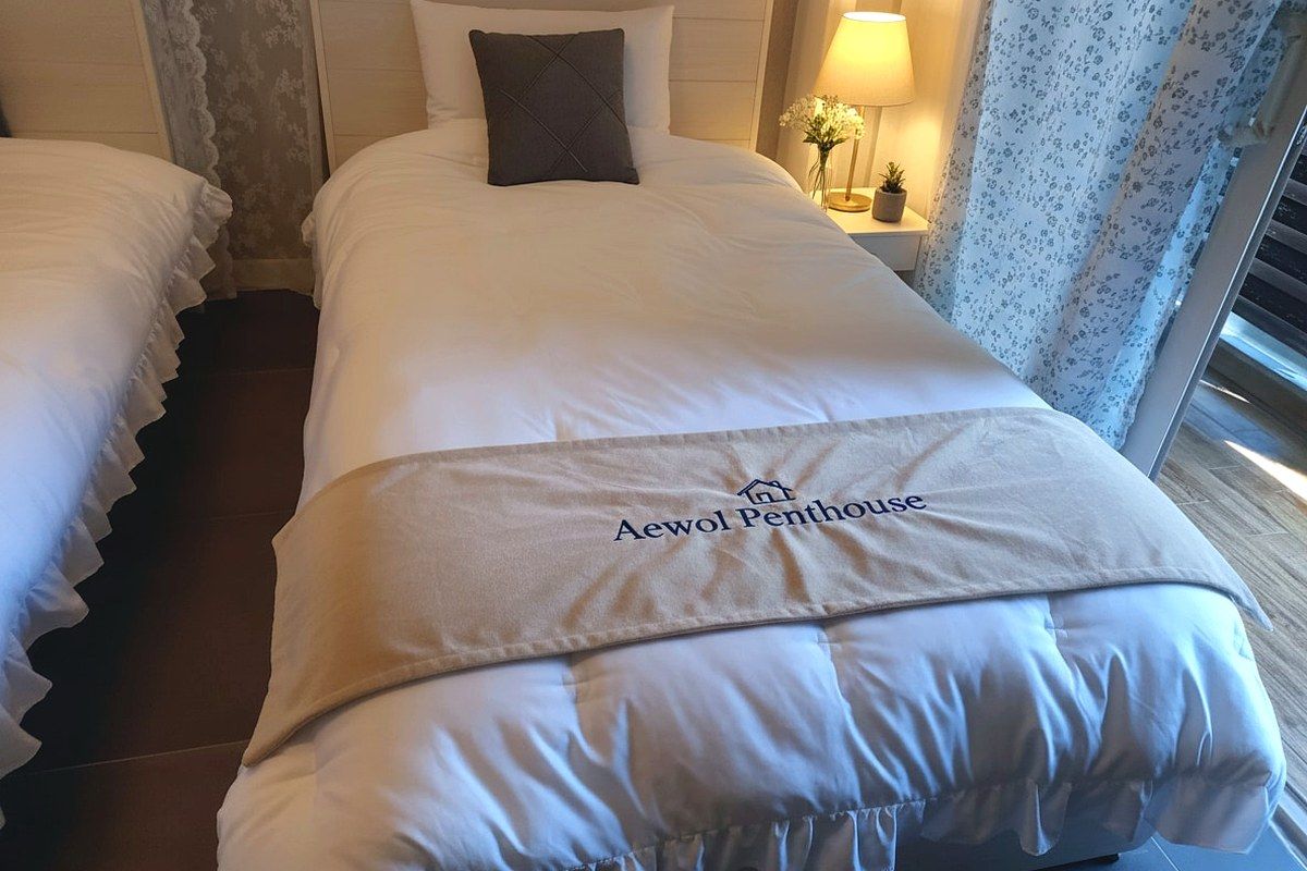 A hotel room with a bed, a nightstand, a lamp, and a window with curtains.