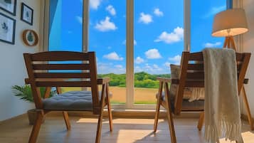 A room with two wooden chairs facing a large window with a view of a green landscape.