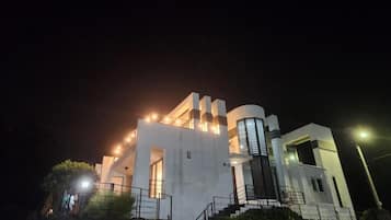 A modern building with a white facade, a cylindrical structure, and a staircase leading up to the entrance.
