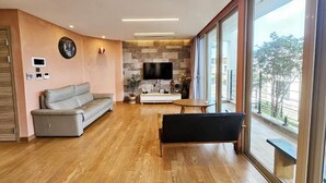 Ein modernes Wohnzimmer mit einer Couch, einer Bank, einem Fernseher und einem großen Fenster mit Blick.