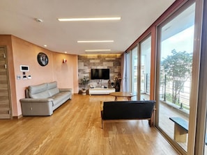 Ein modernes Wohnzimmer mit einer Couch, einer Bank, einem Fernseher und einem großen Fenster mit Blick.
