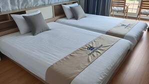 Ein Hotelzimmer mit zwei Betten, einem Holzkopfteil und Blick ins Freie.