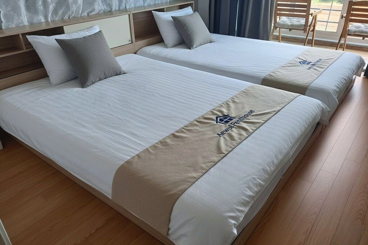 Ein Hotelzimmer mit zwei Betten, einem Holzkopfteil und Blick ins Freie.