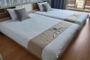 Ein Hotelzimmer mit zwei Betten, einem Holzkopfteil und Blick ins Freie.