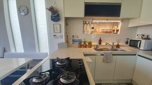 Eine moderne Küche mit Gasherd, Mikrowelle und kleinem Spülbecken.